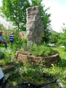 Steinpfeiler als Orientierungspunkt in einem bepflanzten Garten