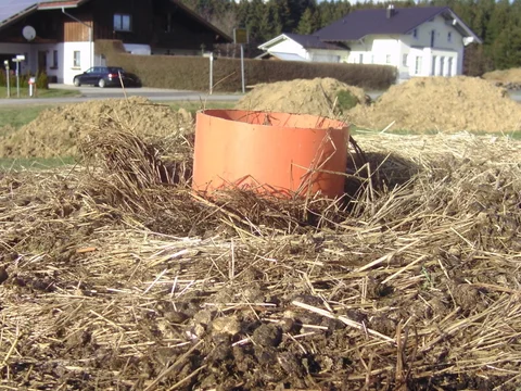 Seitlich gelochtes Gießrohr in der Mitte eines großen Heuballens