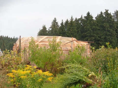Fast geschlossener Gartenpavillon aus Dachlatten auf einer Wiese