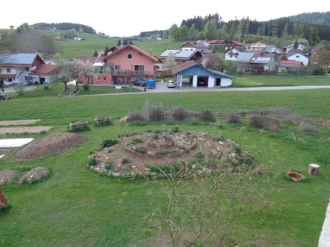 Kräuterspirale und Benjeshecke aus größerer Entfernung im Garten