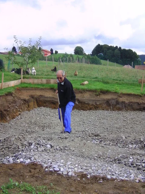 Frostschutzmaterial wird von Hand in der Baugrube verteilt